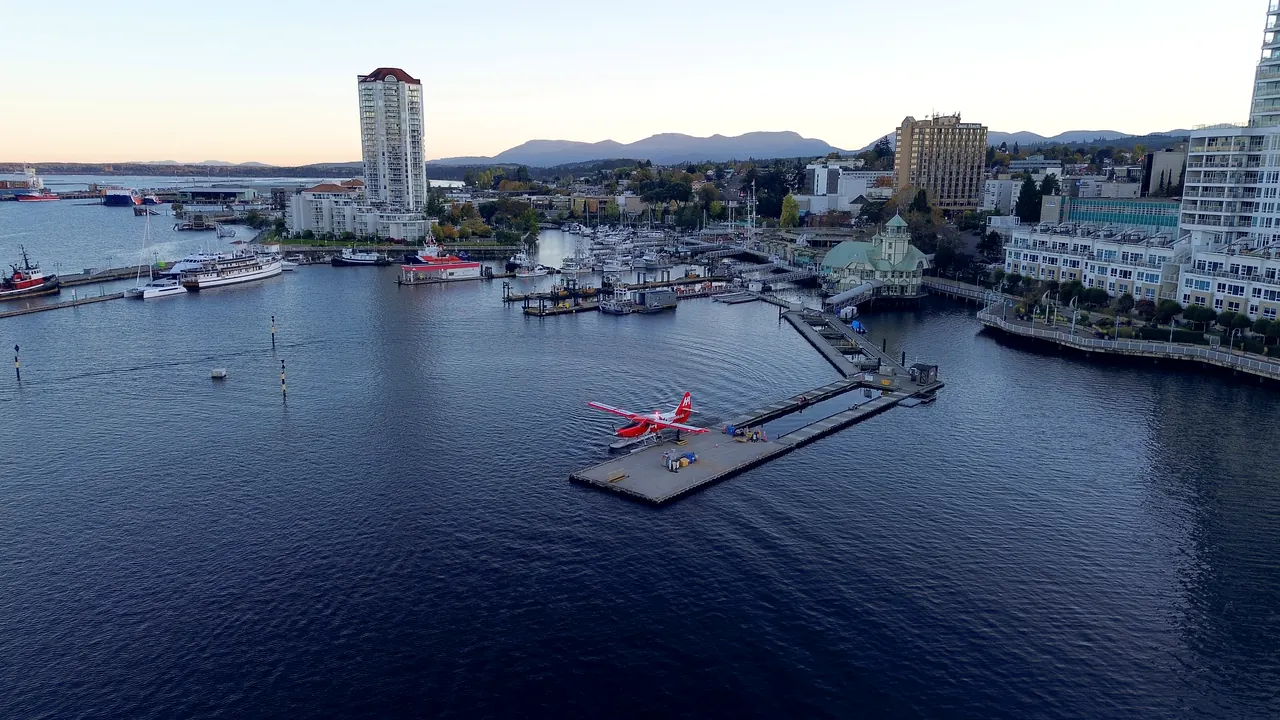 A floatplane at its dock in Nanaimo harbour at dusk, the marina and downtown behind