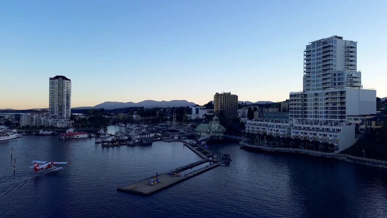 The downtown Nanaimo waterfront from above at dusk, a floatplane on the water